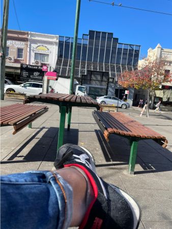 Andrew sitting on a timber bench in the Lackey Street courtyard in Summer Hill during a school reunion visit in June 2021, with the Summer Hill Village Patisserie shopfront visible in the background